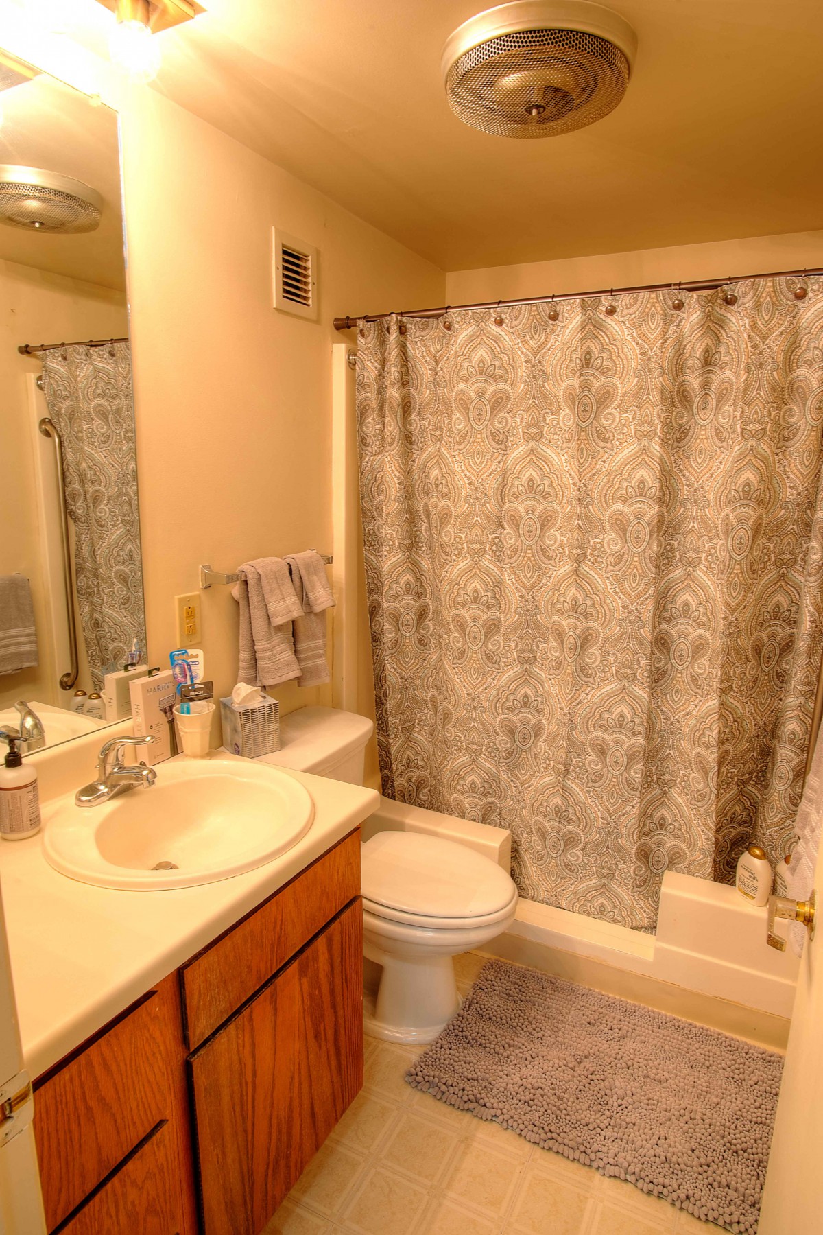 A cozy bathroom with a shower curtain, sink, and mirror.