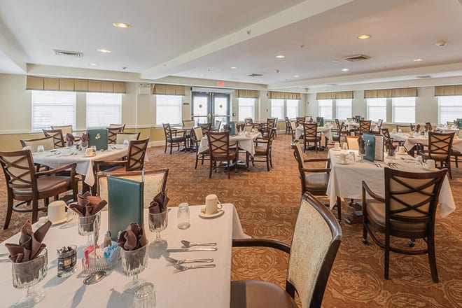 An elegant dining room with neatly arranged tables and chairs, set for service.
