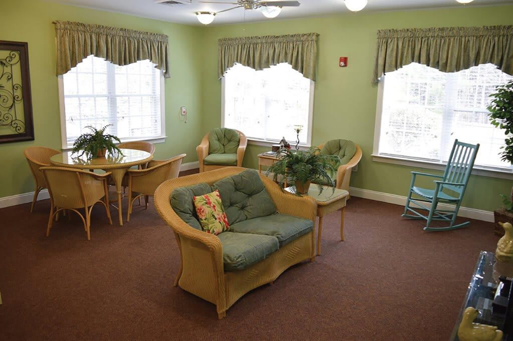 A cozy living room with green walls, comfortable seating, and abundant natural light.