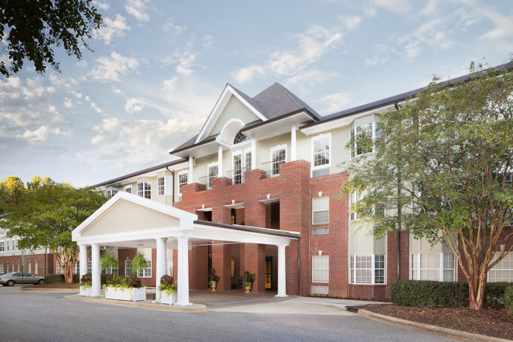 A brick hotel building with a prominent entrance and surrounding trees.