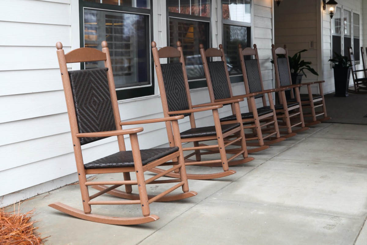 A row of wooden rocking chairs lined up on a porch.