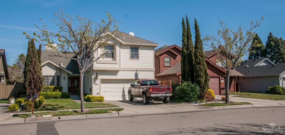 A suburban house with a truck parked in the driveway under a clear blue sky.
