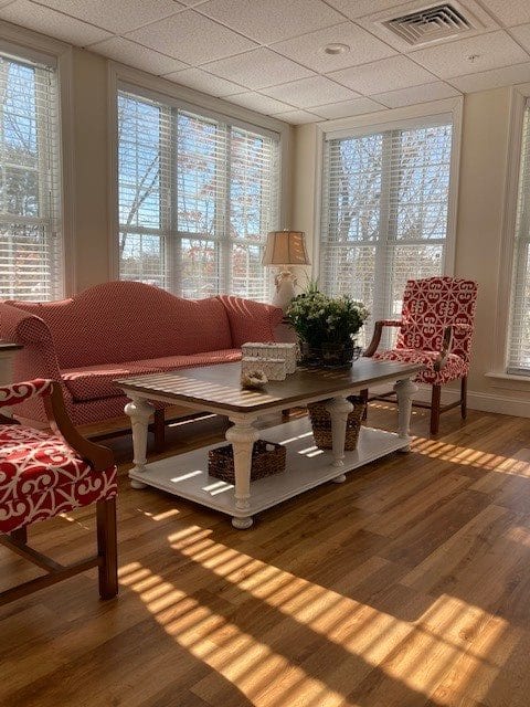 A cozy living room with vintage furniture and sunlight streaming through large windows.