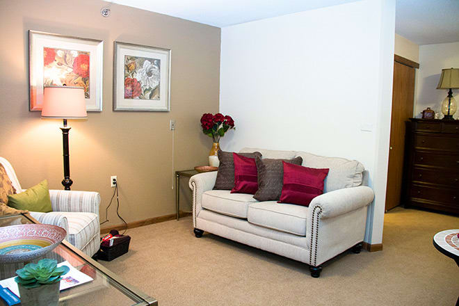 A modern living room with a cozy sofa, decorative pillows, and framed artwork on the wall.