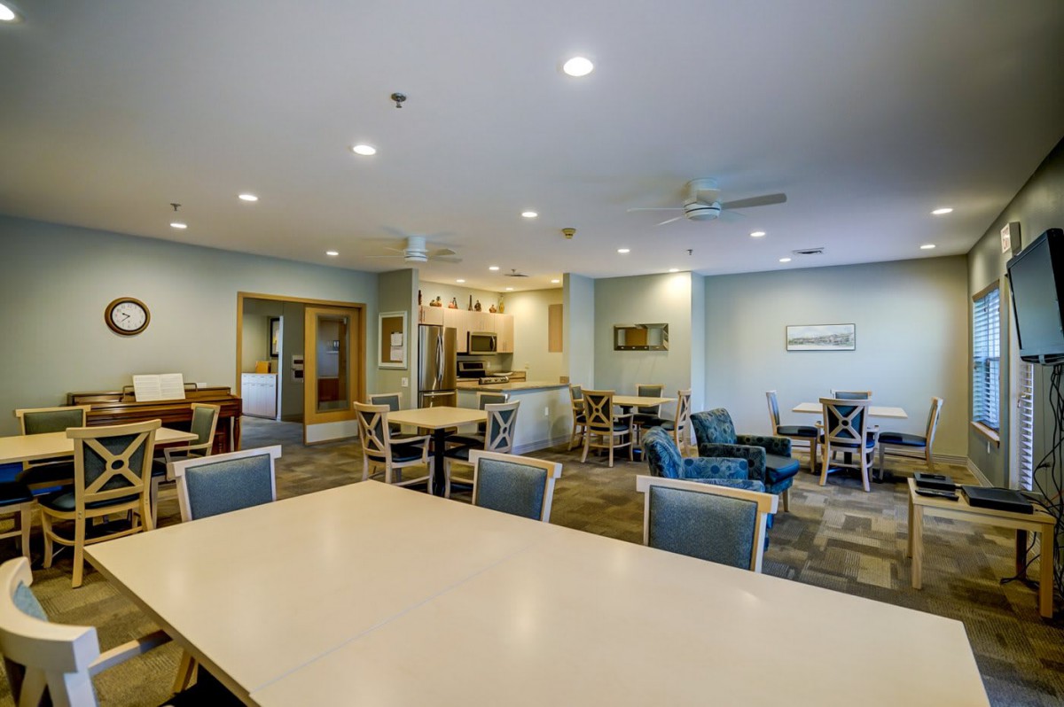 A modern dining area with multiple tables and chairs, featuring ceiling lights in a spacious interior.