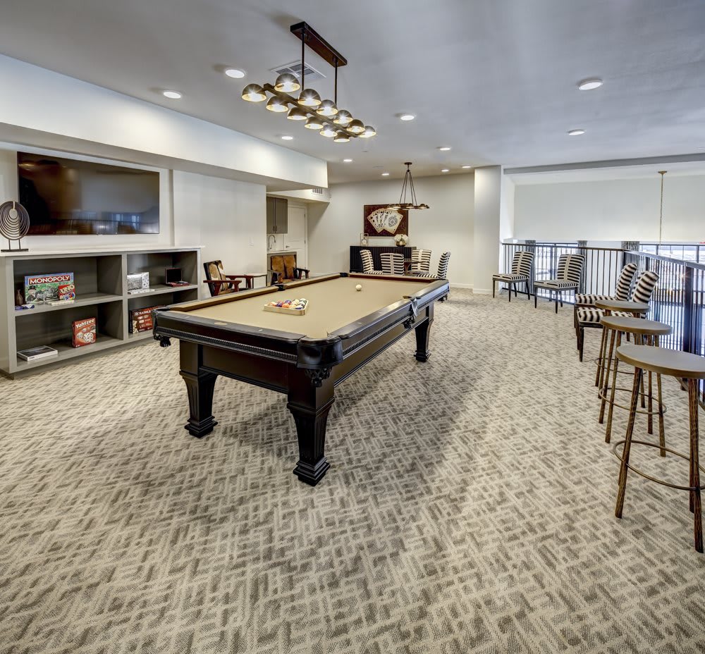 A modern recreation room featuring a pool table and seating area.