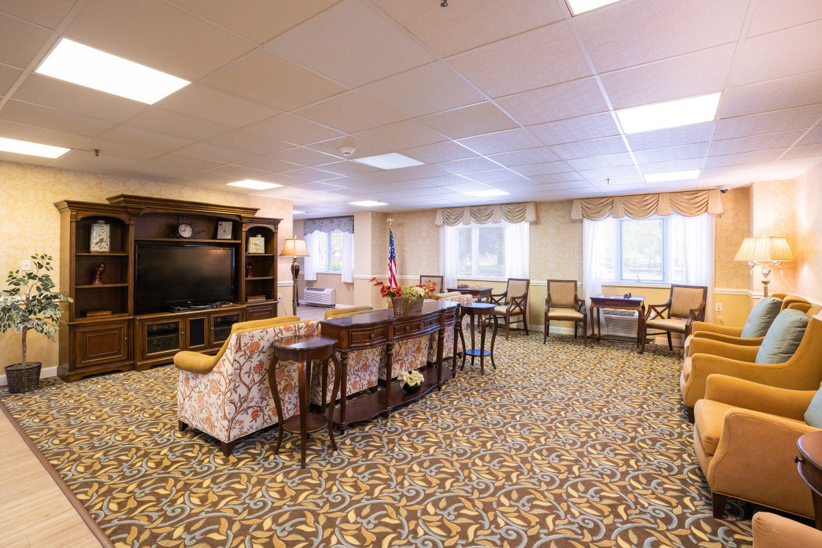 A spacious living room with comfortable seating, wooden furniture, and a large television.