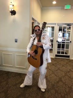 Person dressed in a white suit playing guitar indoors.