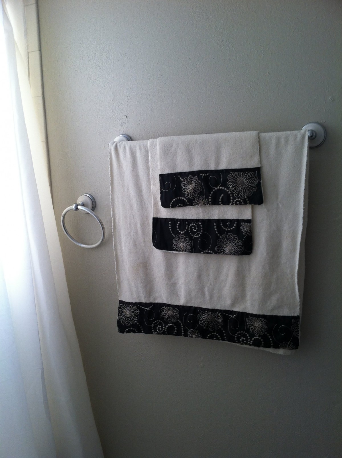 A neatly arranged towel set hanging on a wall-mounted rack in a bathroom.