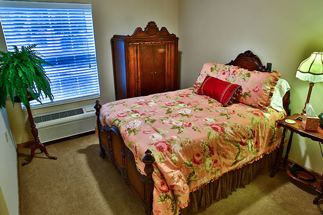A cozy bedroom with antique furniture and floral bedding.