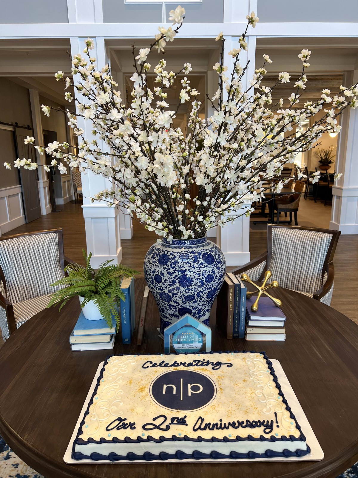 A beautifully set table with a celebration cake and a large vase of white flowers.