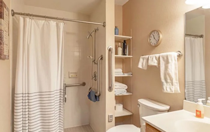 A well-organized bathroom featuring a shower with a curtain, shelves stocked with towels, and essential toiletries.