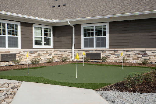 A well-maintained putting green installed in a residential yard, designed for practicing golf skills.