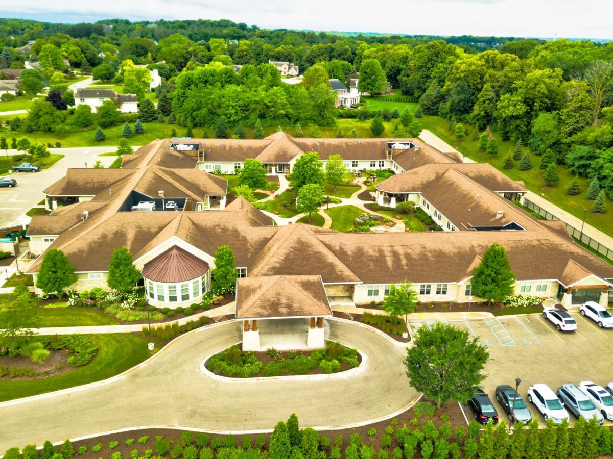 Aerial view of a large building complex surrounded by lush greenery and landscaped gardens.