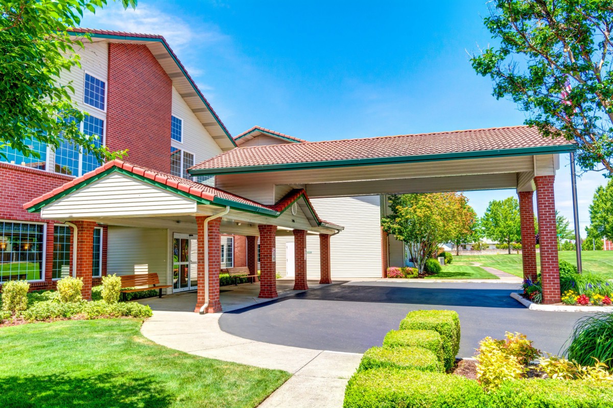 A welcoming hotel entrance with a covered driveway and well-maintained landscaping.