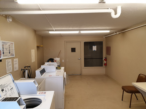 A spacious and well-lit laundry room featuring several washing machines and dryers.