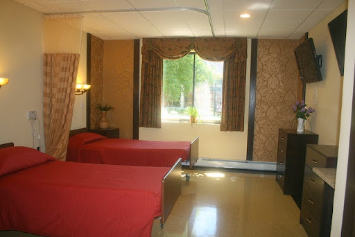 A cozy hotel room featuring two beds with red bedding and a window view.