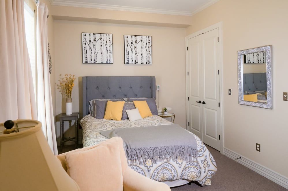 A modern bedroom with elegant decor, featuring a bed with colorful pillows and wall art.