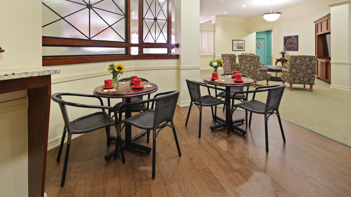 A cozy dining area with neatly arranged tables and chairs, decorated with flowers on each table.
