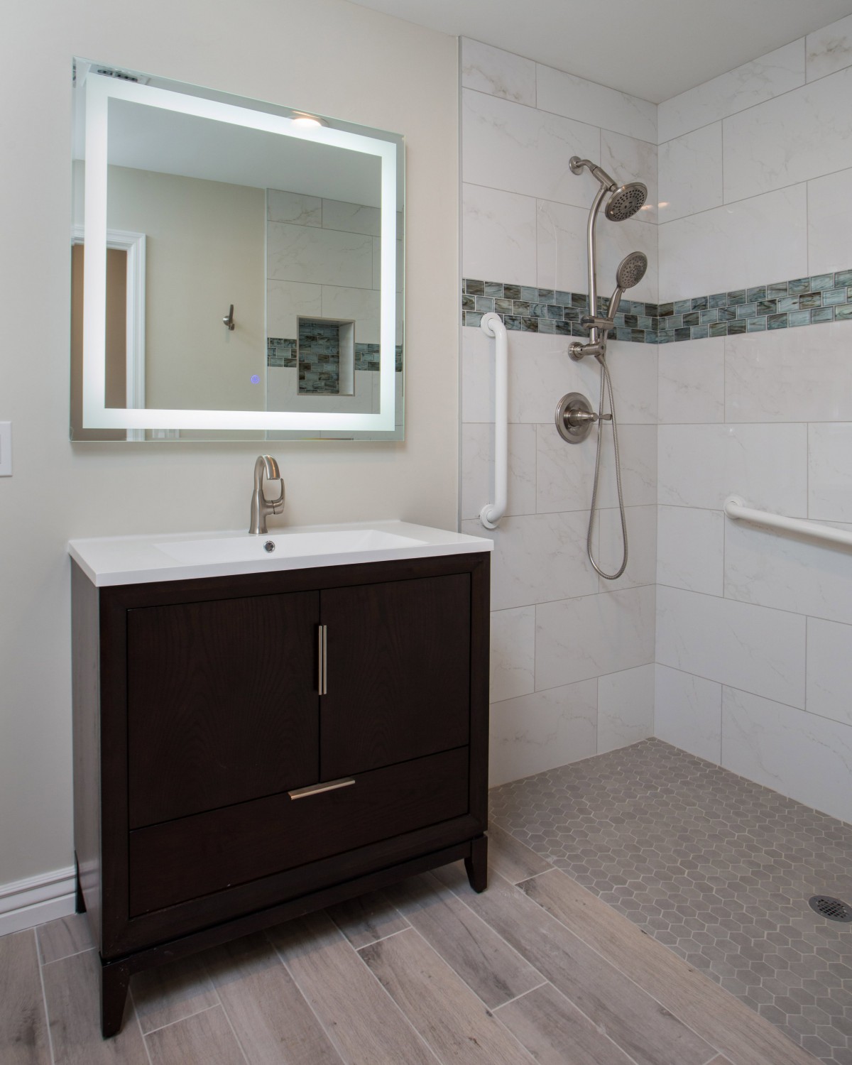 A modern bathroom featuring a vanity with an illuminated mirror and a walk-in shower.