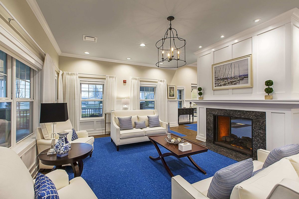 A modern living room featuring white furniture, a blue carpet, and a cozy fireplace.