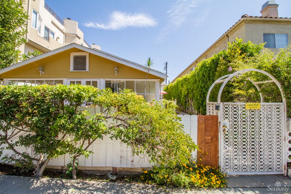 Charming house with a garden and white fence on a sunny day.