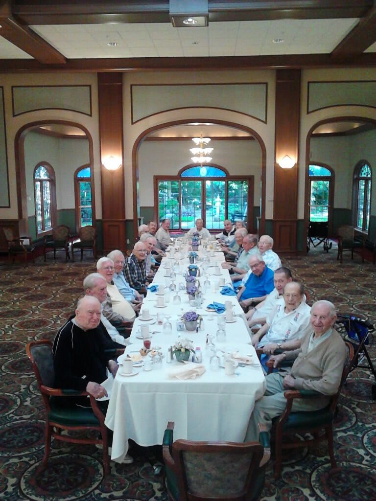 A group of people dining at a long table in a formal setting.