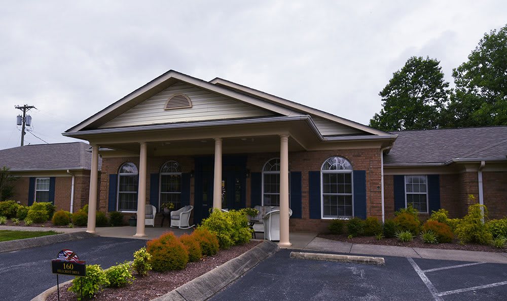A building with a prominent entrance featuring columns and landscaped surroundings.