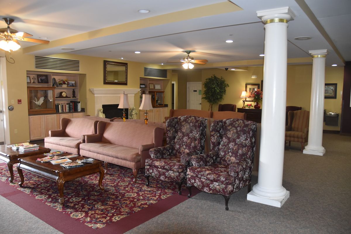 A cozy living room with sofas, armchairs, and a coffee table arranged around a rug.