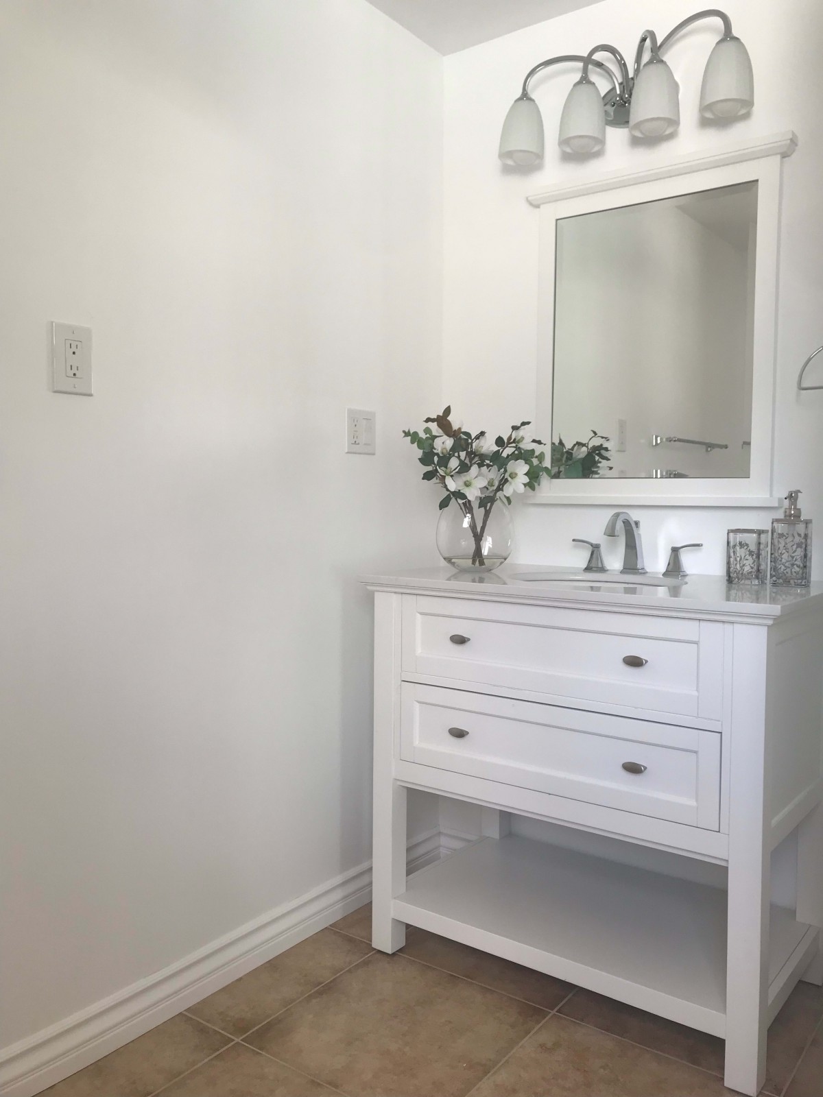 A minimalist bathroom with a white vanity and mirror.