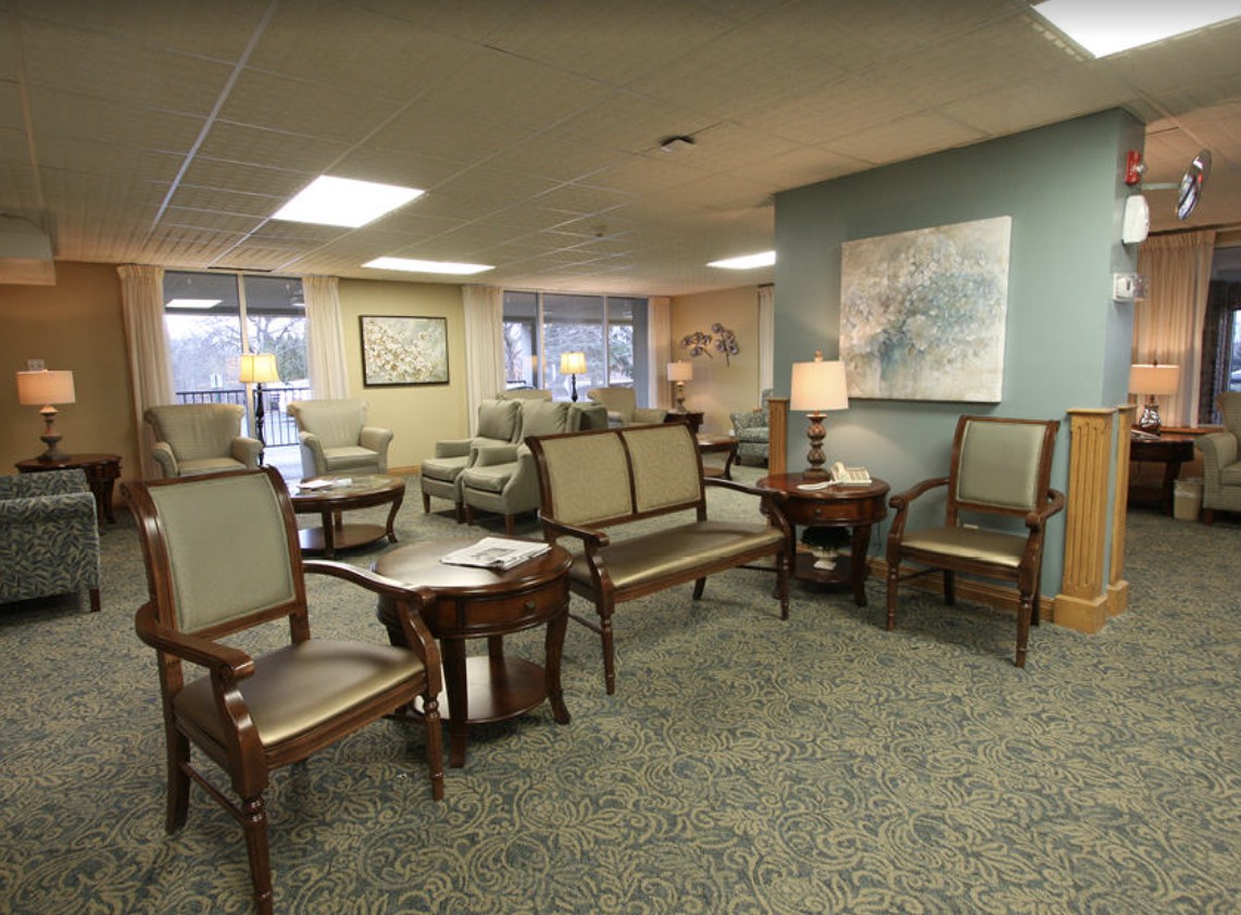A cozy waiting room with chairs, tables, and lamps.