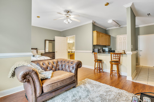 A cozy living room featuring a comfortable sofa, kitchenette, and stylish bar stools.