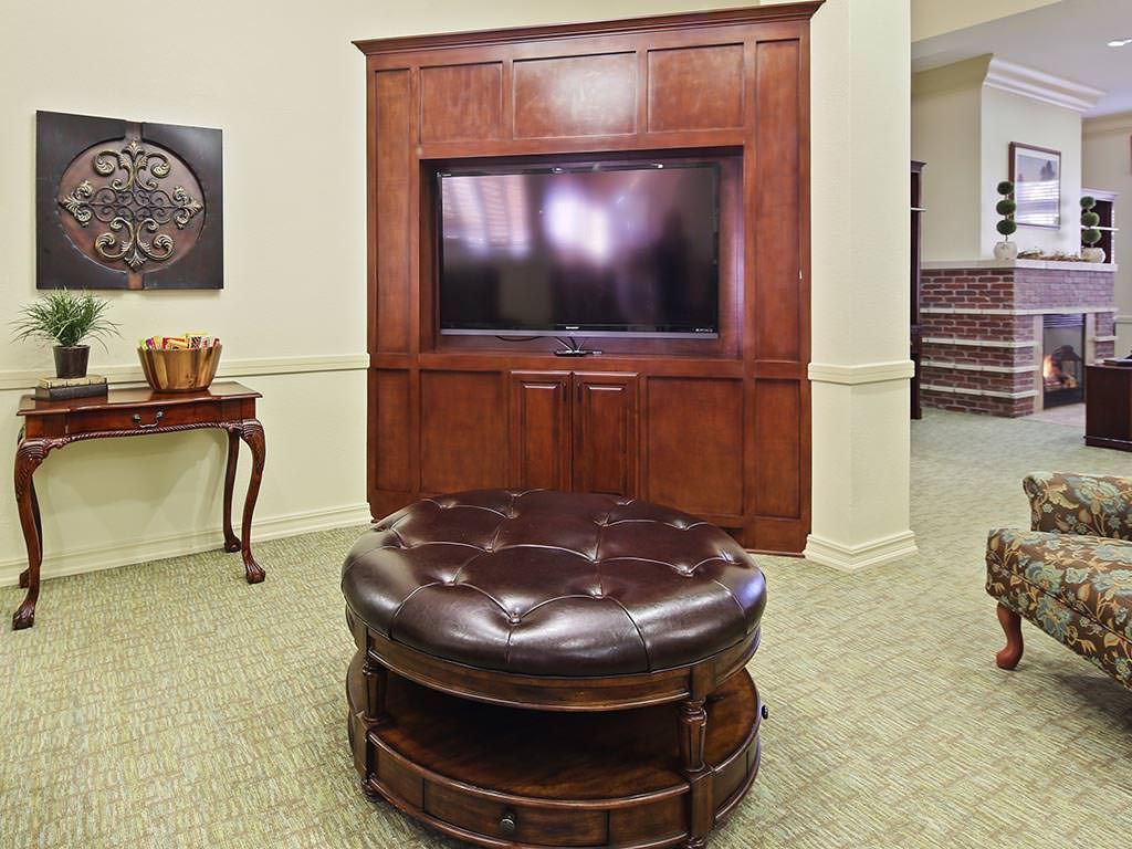 A cozy living room with a mounted television and a leather ottoman.