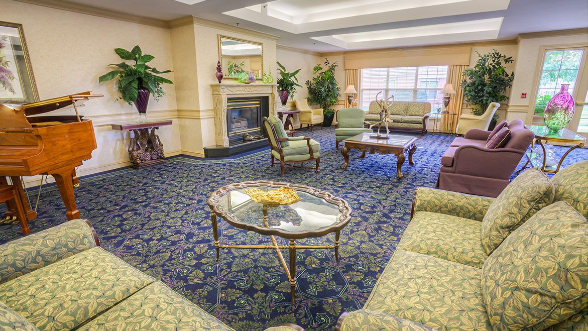 A cozy hotel lobby with sofas, a fireplace, and decorative plants.