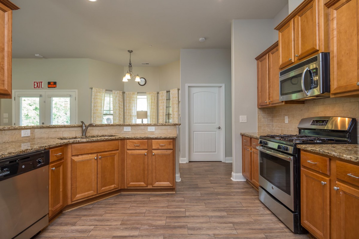 A modern kitchen with wooden cabinets, stainless steel appliances, and a spacious open layout.