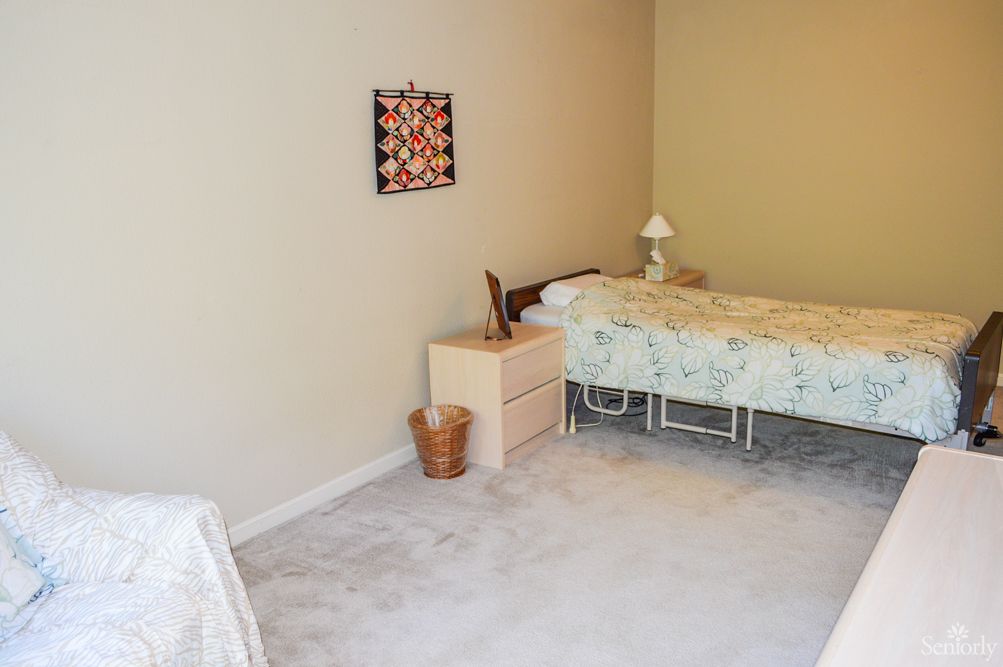 A minimalist bedroom with a single bed, nightstand, and decorative wall art.