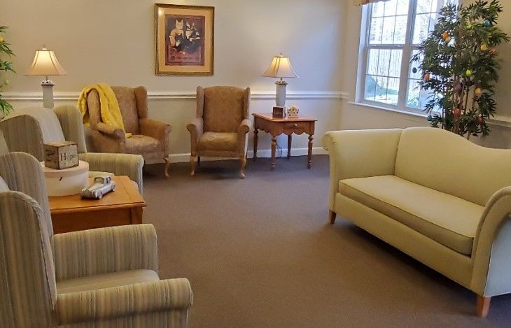 A cozy living room with armchairs, a sofa, and a table under a warm lamp light.