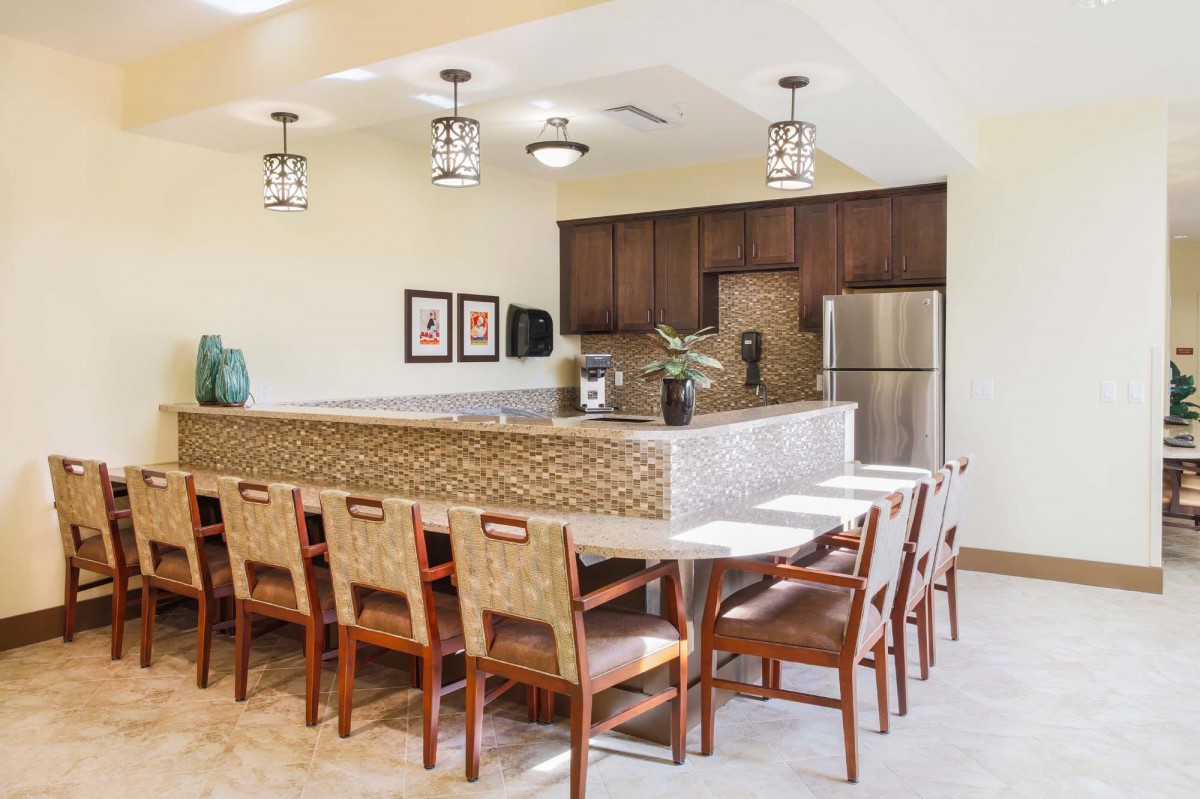 A spacious kitchen and dining area with a long table, wooden chairs, and modern pendant lighting.