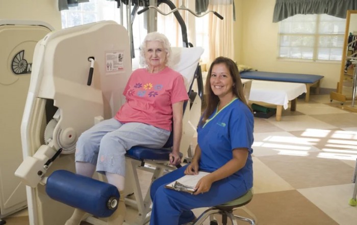 An elderly person undergoing physical therapy with the assistance of a healthcare professional.