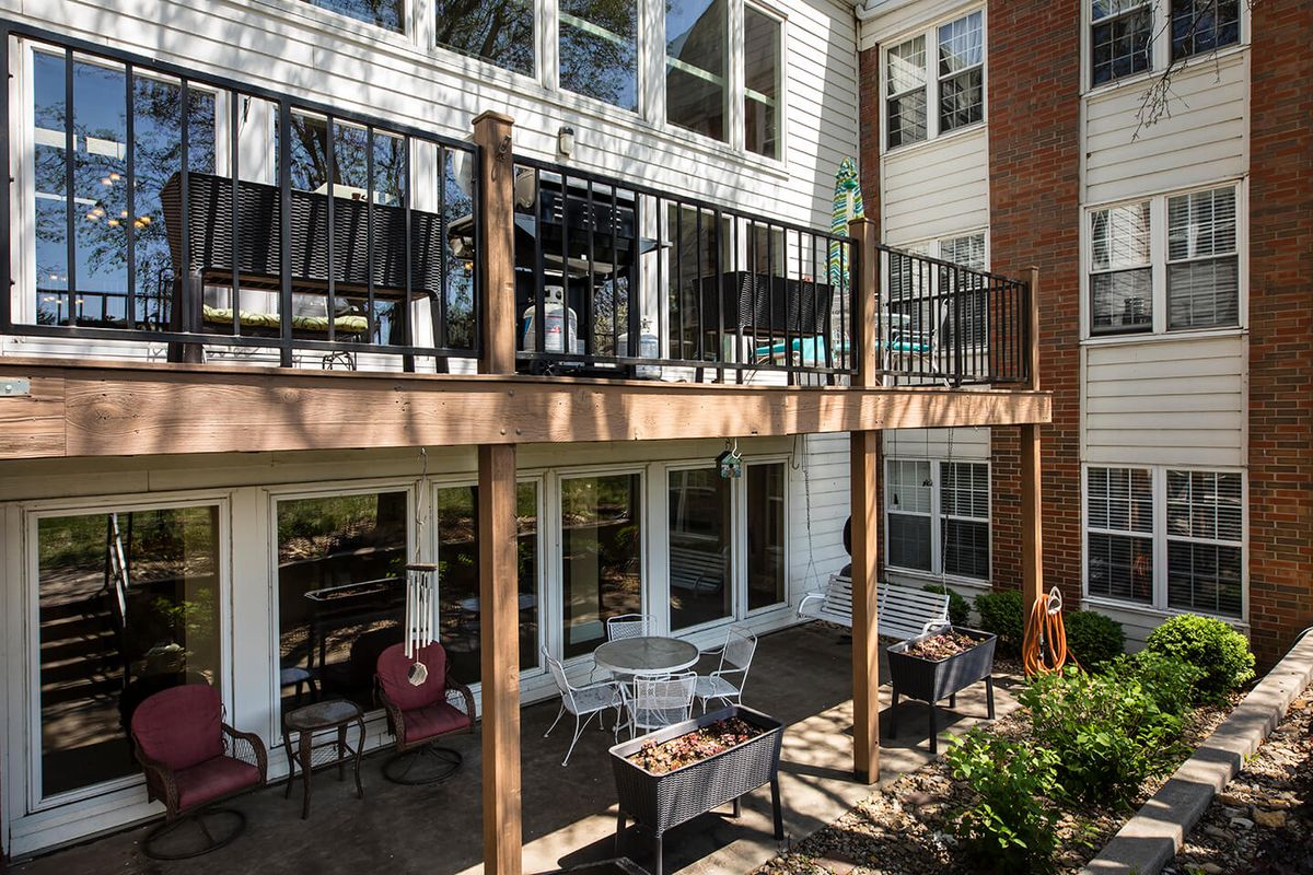 A residential building with a wooden deck and patio area, featuring outdoor furniture.