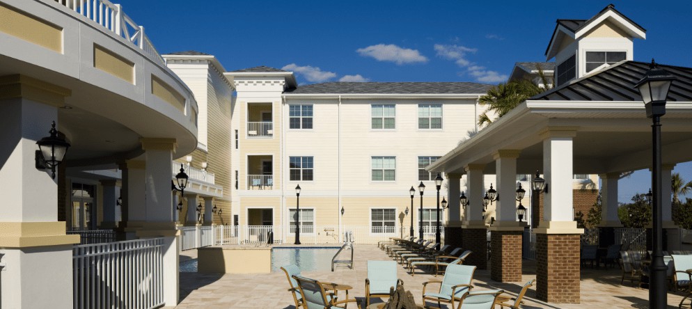 A sunny day at a residential building with a patio area and outdoor seating.