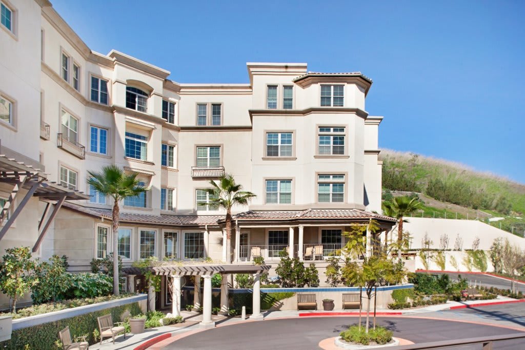 A view of a hotel building with palm trees in front.