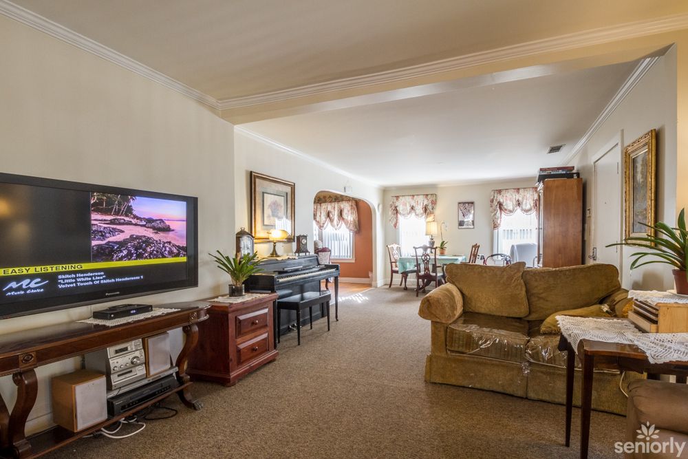 A cozy living room with a television, sofa, and adjacent dining area.