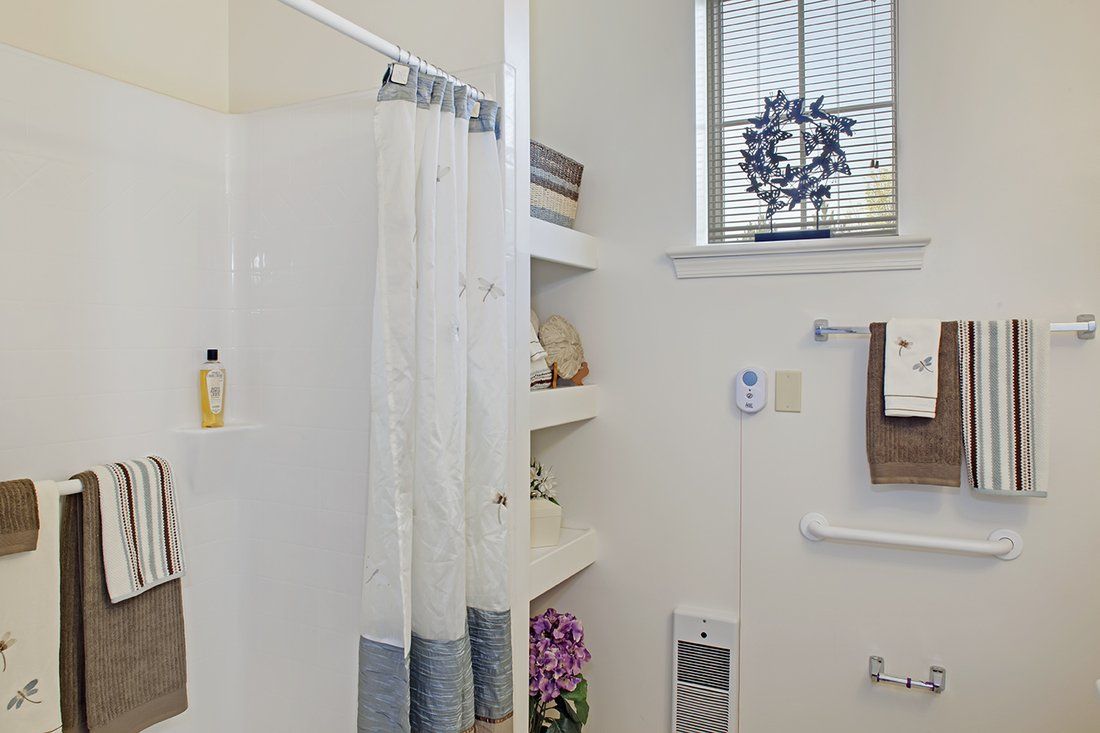 A clean and organized bathroom with a shower, shelves, and decorative items.