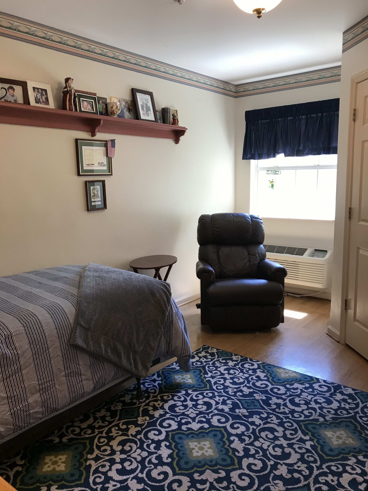 A cozy bedroom with a bed, recliner chair, and large window.