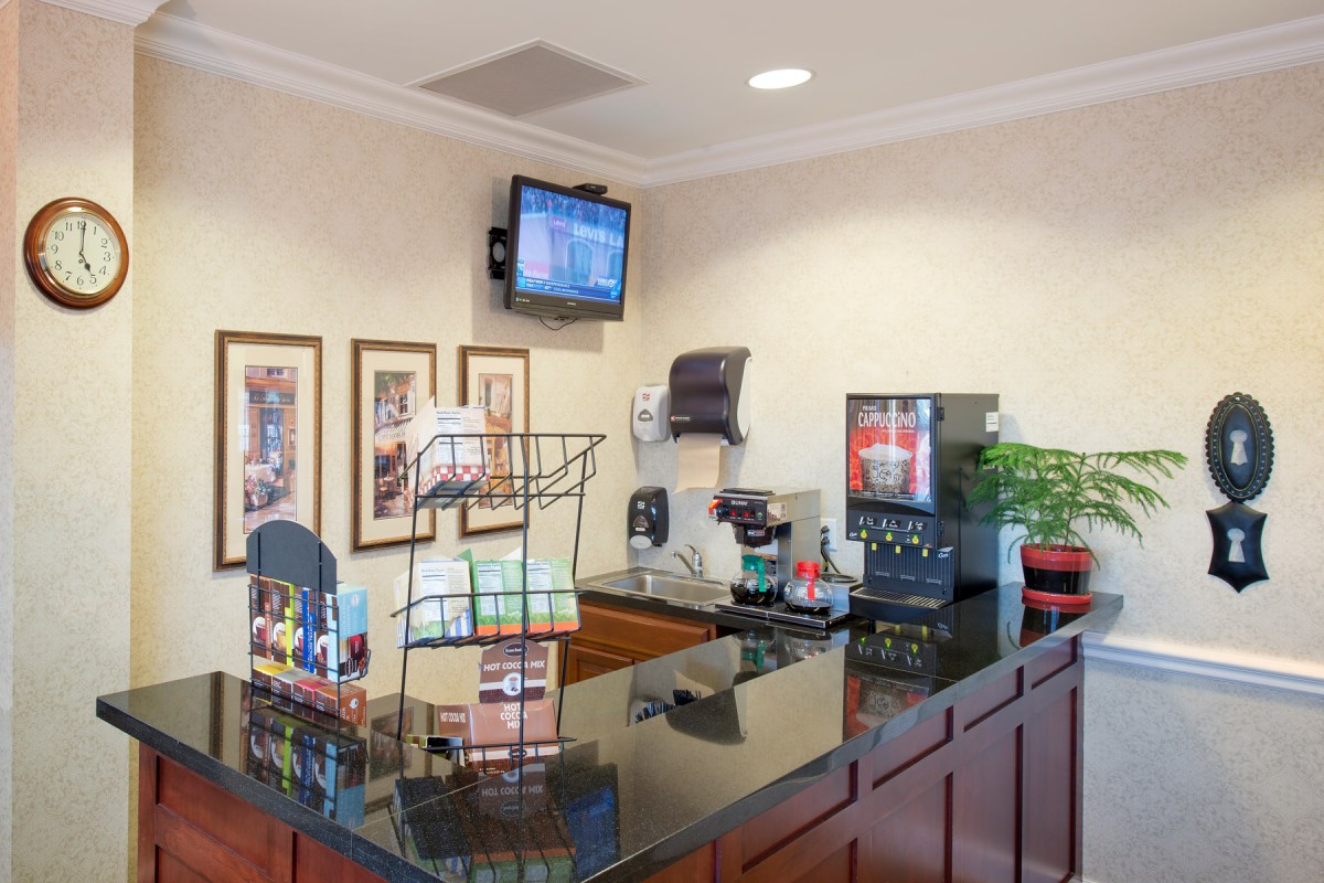 A hotel reception area featuring a coffee station, brochures, and a wall-mounted television.