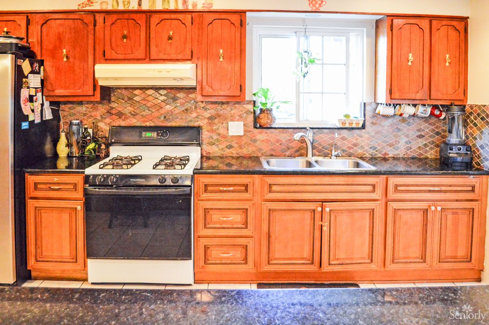 A cozy kitchen featuring wooden cabinets, a stove, and a sink under a window.