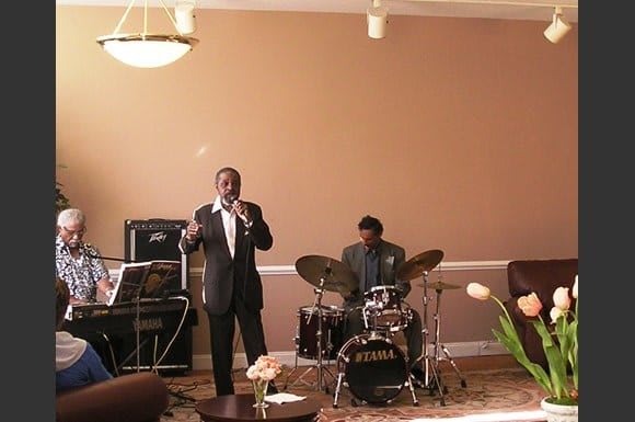 A band performing live indoors with a singer and drummer.