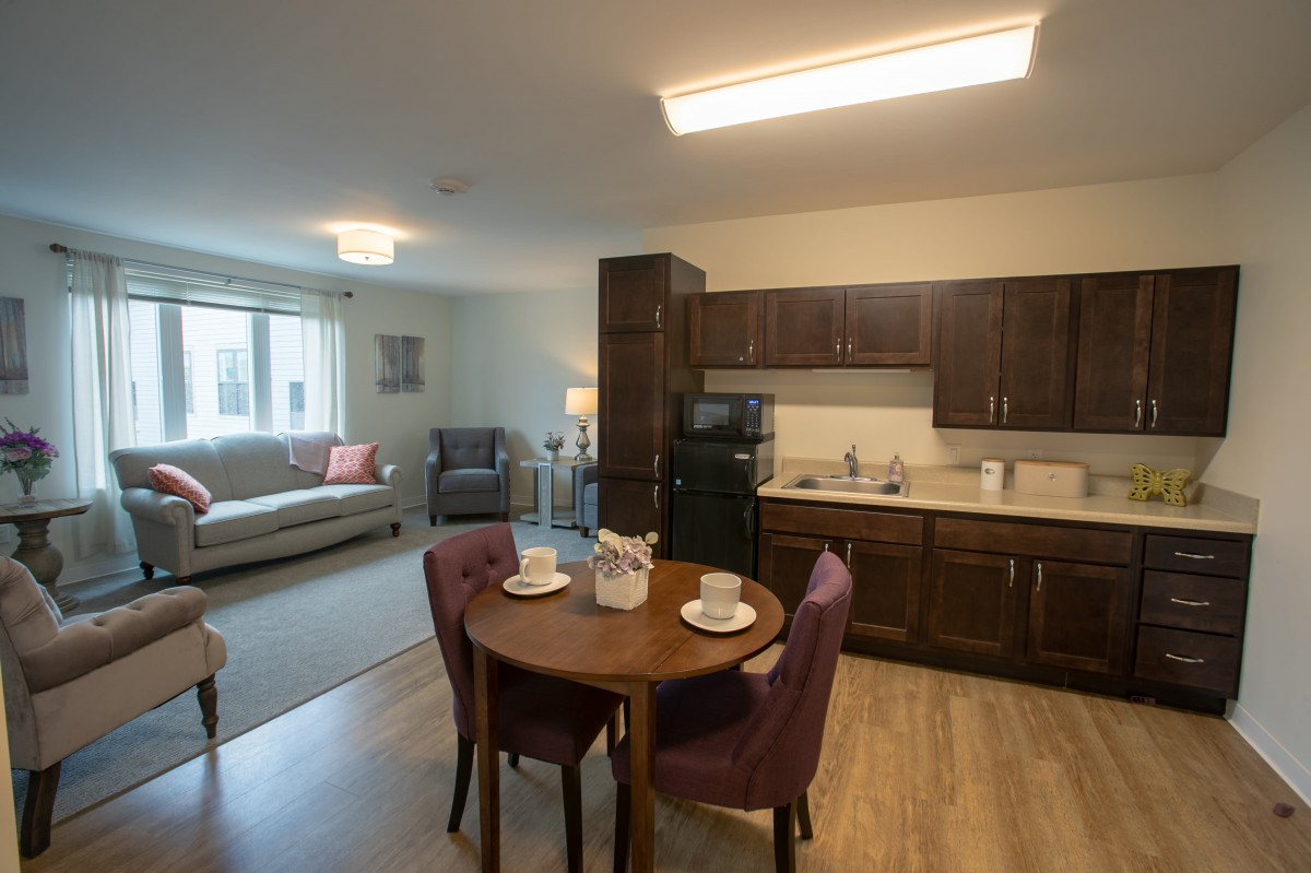 A modern apartment interior featuring a combined living room and kitchen area with a small dining table.