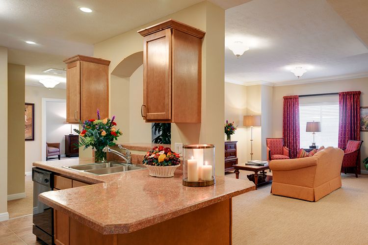 A cozy open-concept kitchen and living room featuring wood cabinets, a spacious countertop, and warm lighting.